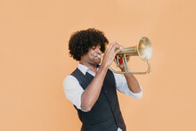 Man With Eyes Closed Playing Trumpet In Front Of Beige Wall