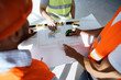 © fotofabrika - Close up of three man engineers looking at blueprint on construction site