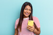 © Asier - Young Venezuelan woman holding mobile phone isolated on blue background happy, smiling and cheerful.