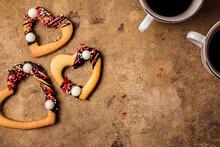 Studio Shot Of Heart Shaped Cookies And Two Cups Of Coffee Standing Against Brown Background