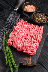 Wall Mural - Raw mince lamb, ground meat with herbs and spices on a wooden cutting board. Black wooden background. Top view