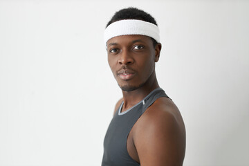 Wall Mural - Horizontal close-up image of handsome young African American man wearing sleeveless T-shirt, looking at camera with positive and thoughtful face expression. Human emotions and feelings