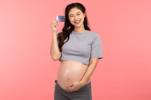Asian Pregnant Woman Holding Credit Card Smile And Happiness Isolated On Pink Background.Cheerful Pregnancy Woman Enjoy With Credit Card To Shopping Baby Stuff.Pregnancy Prepare For Newborn Concept
