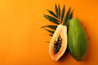 Ripe papaya with leaves on orange background