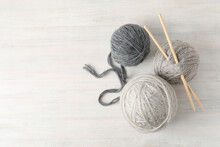Yarn Balls And Knitting Needles On White Wooden Table