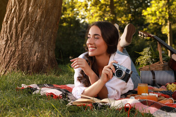 Wall Mural - Happy young woman with camera on plaid in park. Summer picnic