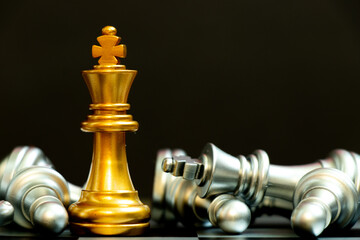 Wall Mural - Gold king chess piece win over lying down silver team on black background