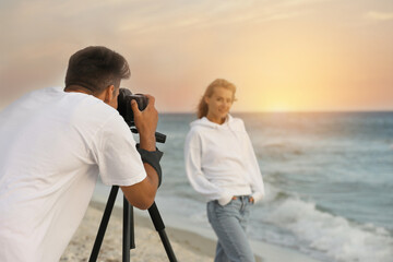 Sticker - Photographer taking picture of model with professional camera near sea