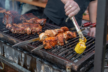 Wall Mural - The cook grills corn and meat on a spit. BBQ vegetables and meat