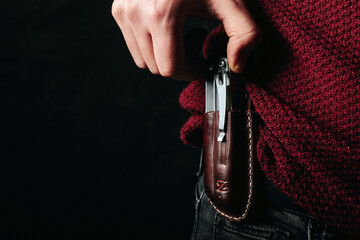 Poster - Closeup of the man taking the knife out from a leather scabbard.