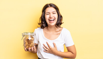 Wall Mural - young hispanic woman laughing out loud at some hilarious joke. cookies bottle concept