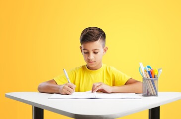 Wall Mural - Back to school. Happy little pupil at the desk. Child doing homework