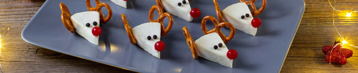 Wall Mural - banner of Funny christmas snack in a shapes of deer for kids party. Concept New year food from cheese and pretzels