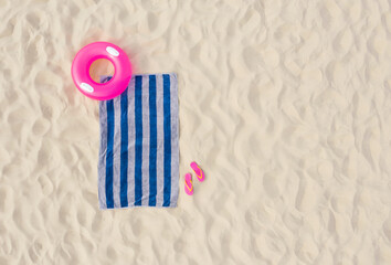 Wall Mural - Striped beach towel, flip flops and swim ring on sand, aerial view. Space for text