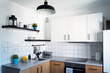 Interior of kitchen with white tiles and cabinets, kitchen counter top and shelf with utentils. Cozy room in apartment. 