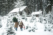 © Westend61 - Man carrying tree while walking with woman on snow