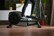 Legs of woman training on elliptical bike in living room at home