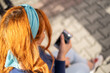 © Jovan - a young girl with orange hair and a blue scarf looks at her mobile phone