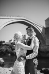 Poster - Vertical grayscale shot of glamourous bride and groom at the Old Bridge in Bosnia and Herzegovina