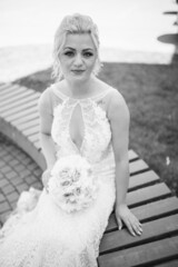 Poster - Vertical grayscale shot of a smiling bride from Bosnia and Herzegovina sitting holding her bouquet