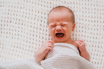 Wall Mural - Closeup portrait of crying newborn baby boy. Soft focus.