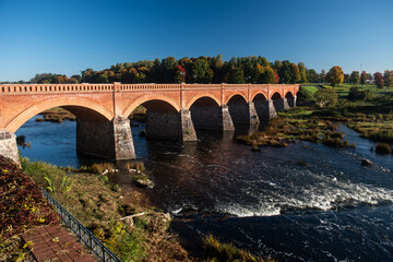 Wall Mural - Long red brick bridge in sunny autumn morning, Kuldiga, Latvia.