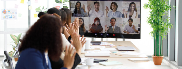 Close up shot of multicultural businessman businesswoman colleagues on teleconference on monitor screen greeting say hello to female officer staffs group in formal suit sitting waving hands together