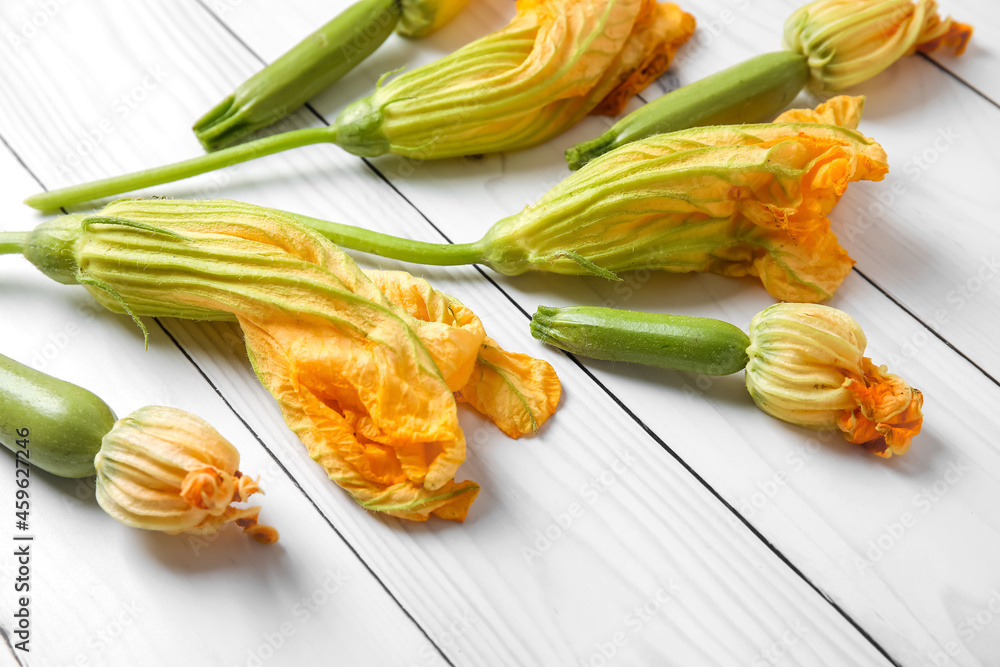Fresh zucchini with flowers on white wooden background, closeup