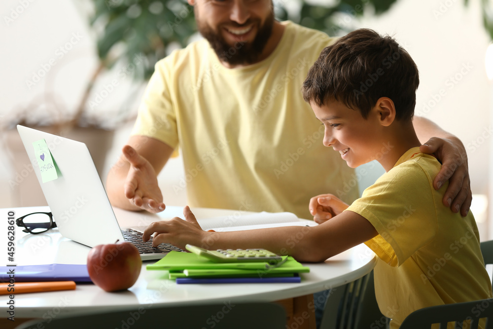 Little boy with his father doing lessons online at home