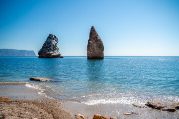 Two rocks stick out of the water in the middle of the turquoise sea. Scenic ocean views. High quality photo. Like in Iceland