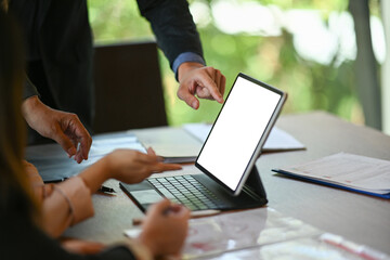 Two businesspeople discussing business data on computer tablet and discussing business ideas together.