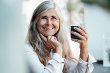 Smiling Mature Woman Holding Coffee Cup In Cafe