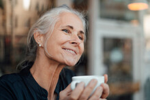 Smiling Woman Holding Coffee Cup In Cafe