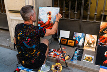 Male Artist Painting Female While Sitting On Footpath