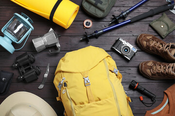 Wall Mural - Flat lay composition with backpack and other camping equipment for tourism on wooden background