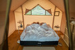 © pressmaster - Tired young couple sleeping on large double bed under white sheets in glamping tent