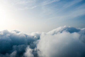 Wall Mural - View from above, drone point of view, stunning aerial shot of some fluffy clouds with a bright sun.