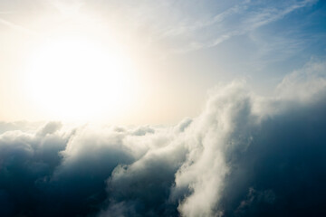 Wall Mural - View from above, drone point of view, stunning aerial shot of some fluffy clouds with a bright sun.