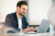 © Westend61 - Happy young businessman using laptop while sitting at desk in office