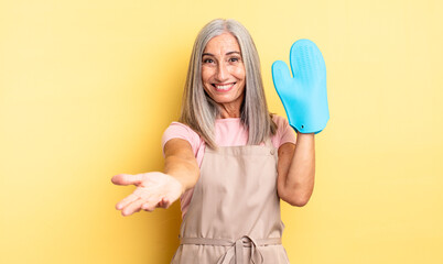 middle age pretty woman smiling happily with friendly and  offering and showing a concept. oven mitt concept