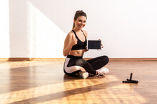 Sportive Woman Holds Tablet With Empty Screen, Showing Thumb Up, Recommend Online Fitness Course, Wearing Black Sports Top And Tights. Full Length Studio Shot Illuminated By Sunlight From Window.