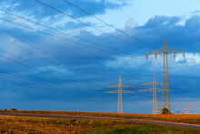 Electricity Pylons Standing Against Blue Cloudy Sky
