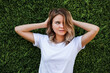 © Irina Magrelo - Young woman in white shirt with natural makeup standing by green hedge