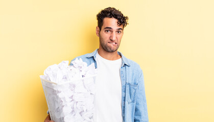 Wall Mural - hispanic handsome man looking puzzled and confused. paper balls trash concept