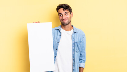 Wall Mural - hispanic handsome man shrugging, feeling confused and uncertain. empty canvas concept