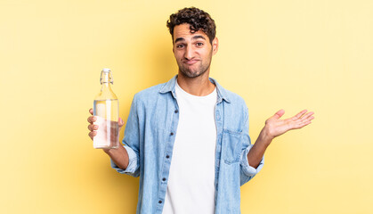 Wall Mural - hispanic handsome man feeling puzzled and confused and doubting. water bottle concept