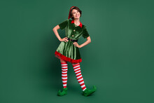 Photo Of Funny Positive Cheerful Helper Lady Hands Hips Wear Elf Costume Hat Stockings Isolated Green Color Background