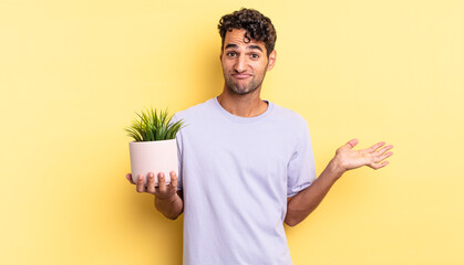 Wall Mural - hispanic handsome man feeling puzzled and confused and doubting. decorative plant concept