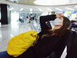 © SHOTPRIME STUDIO - a woman with a yellow backpack sits at the airport long waiting for a flight
