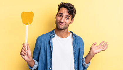 Wall Mural - hispanic handsome man feeling puzzled and confused and doubting. kills flies concept